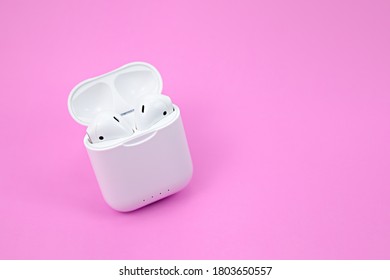Wireless bluetooth headphones and charging case on pink background
