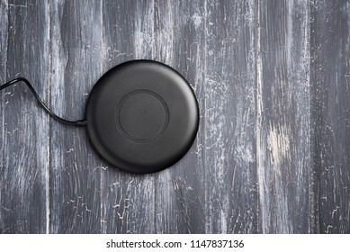 Wireless charger for mobile phone on vintage wooden gray background, top view
