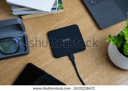 Wireless charging pad placed on a wooden work table, top view