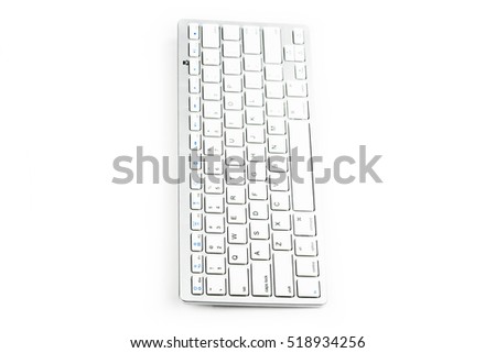 Wireless computer keyboard isolated on white background. Modern aluminum computer keyboard. Close up of white-silver  wireless aluminum fingerboard with english letters. Side view.