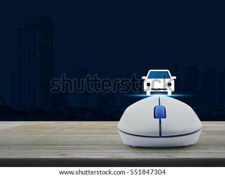 Wireless computer mouse with car front view flat icon on wooden table over city tower, Internet service car concept