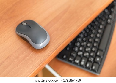 Wireless computer mouse and keyboard on wooden table.