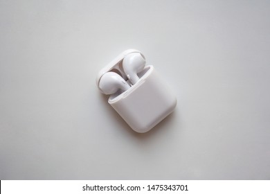 Wireless ear buds in glossy white plastic case isolated on white background