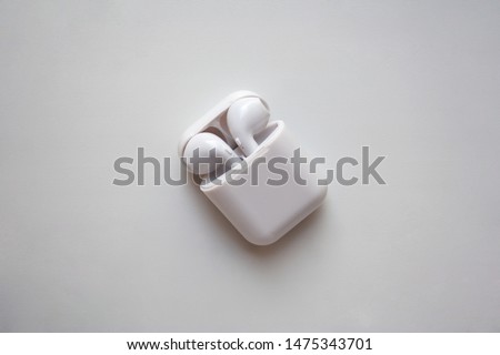 Wireless ear buds in glossy white plastic case isolated on white background
