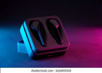 Wireless earphones / earbuds on a dark dual tone background. Earphone / earbuds close up in the charging case close-up.