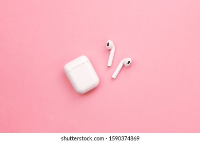 Wireless earphones on pink background. Flatlay.