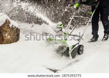 Wireless electric snow blower at work. Rechargeable battery machine.