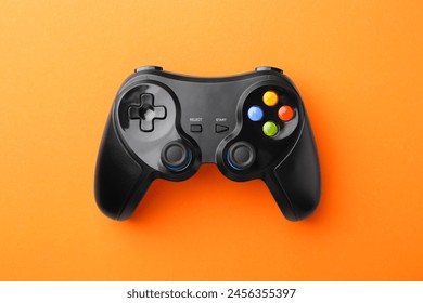 Wireless game controller on orange background, top view