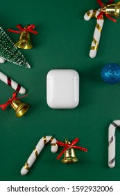 Wireless Headphones On Green Christmas Background. Airpods. Air Pods. With Wireless Charging Case. Entangled 3.5 Headphones. Copy Space