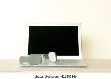 Wireless headset and Computer laptop on wooden table