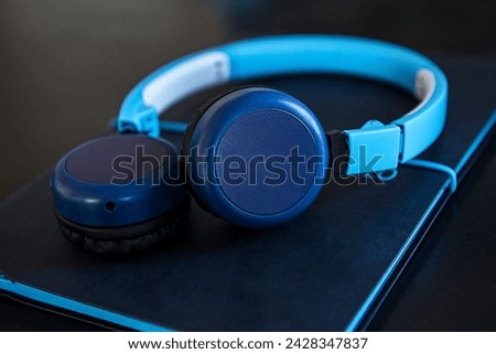 Wireless headset resting on notebook on desk, business setting, blue tones