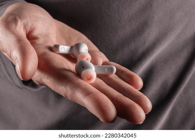 Wireless in-ear white headphones in hand.