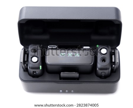 A wireless microphone charging case is open on a white background, revealing two transmitters and a receiver inside