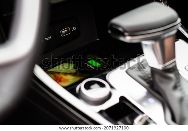 Wireless\
mobile charger in the modern car. Portable wireless car charger for\
smartphone. Phone charging on  wireless\
charger.