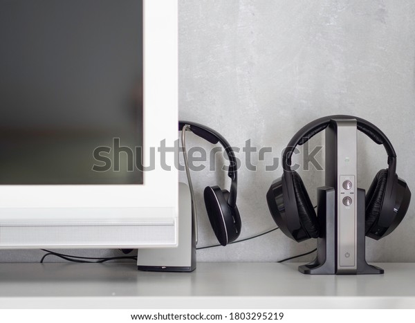 Wireless\
noise-canceling black headphones charging next to a television for\
watching tv or listen to music at\
home.