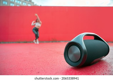 Wireless outdoor portable speaker mockup playing music on dance floor on red background with copy space for advertising