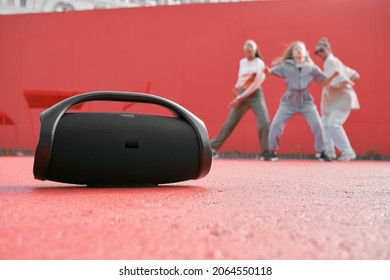 Wireless Outdoor Portable Speaker Playing Music On Dance Floor On Red Background With Dancing Girls. Product Placement