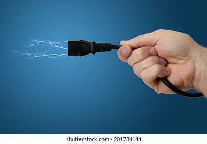 Wireless Power A Hand Holding A Plug With Electricity Firing From The End On A Blue Gradient Background