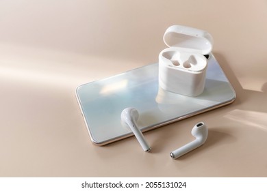 Wireless Technology, Modern Tech. Minimal Shot Smartphone And Of A Pair Of White Wireless Headphones On A Pastel Neutral Colors Background. Copy Space.