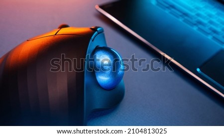 Wireless Trackball Computer mouse near the laptop on a blue background