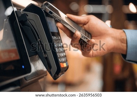 Wireless transfer. Close up view of man customer that is paying for products by credit card in grocery store.