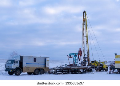 Wireline Equipment Hanging From Top Drive Ready To Be Lowered Downhole For Logging. An Oil Well Engineer Works From The Back Of Specialised Van To Log The Condition Of Steel Casing Inside An Oil Well