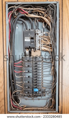 Wires running to and from an electrical panel with different sized circuit breakers and fuses plus missing, damaged and dirty parts.