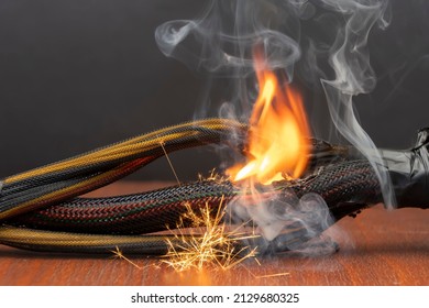 The wiring is burning and sparking on a dark background. A short circuit in the twisted wires from the computer. Flames, sparks and smoke.