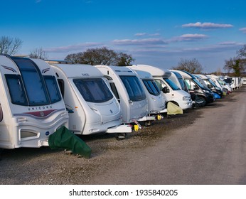 Wirral, UK - Mar 6, 2021: A Row Of White Touring Caravans On Hardstanding In A Secure Caravan Storage Facility On A Sunny Day In Winter With A Blue Sky.