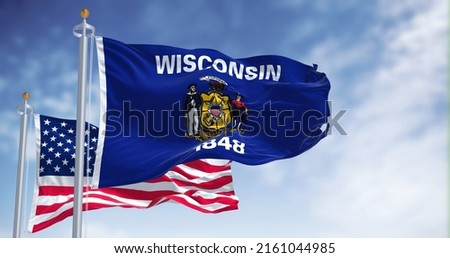 The Wisconsin state flag waving along with the national flag of the United States of America. Wisconsin is a state in the upper Midwestern United States