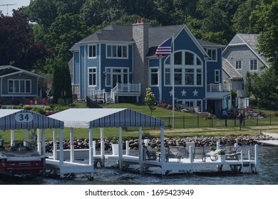 Wisconsin, USA; June 23, 2019: Lakefront houses along the shore of Lake Geneva, with the typical boat docks and wooden deck.