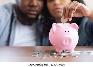 Wise Family Budget Planning. Serious Black Couple Putting Coin To Piggy Bank, Saving Money For Future, Estimating Spends