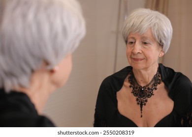 Wise looking senior woman looking at her reflection  - Powered by Shutterstock