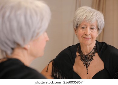 Wise looking senior woman looking at her reflection  - Powered by Shutterstock