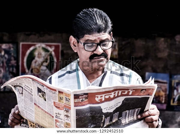 a wise man reading\
news paper on the street in kolkata, west Bengal, India. In the\
month of January 2019.