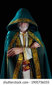 The wise old wizard wearing a hooded cloak. The hood is pulled over the face, the eyes are not visible. The wizard folded his arms over his chest. He is plotting a sinister sorcery.