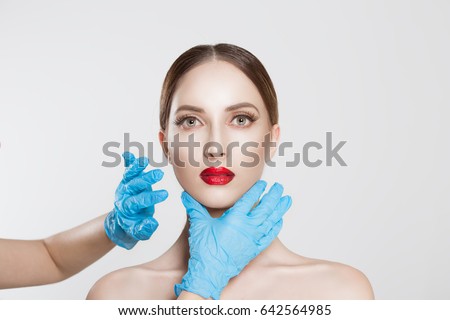 wish to be beautiful need for beauty. Closeup portrait doctor hands with gloves touching woman face chin lips chin want to change her form do plastic surgery. Lips augmentation chin reduction concept