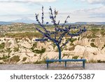 Wish tree with blue glass evil eyes (nazar boncugu) signs. Cappadocia landscape and mountain in snow as background. Goreme, Turkey