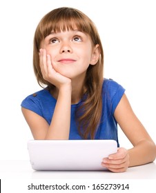 Wishful thinking young girl is using tablet while sitting at table, isolated over white