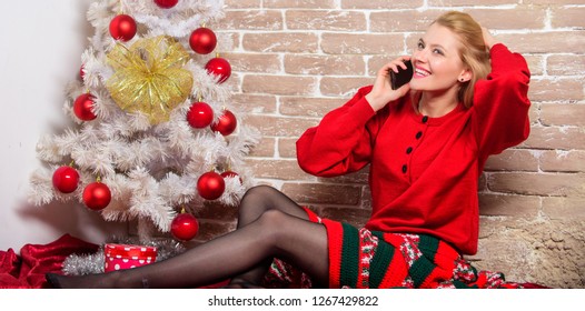 Wishing Everyone Merry Christmas. Waiting For Christmas. Voicemail Greeting. Woman Cheerful Hold Smartphone Enjoy Mobile Phone Conversation. Girl In Dress Sit Near Christmas Tree With Ornaments.