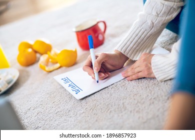 Wishlist. Woman sitting on the floor and writing her wishlist