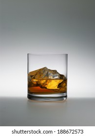 Wiskey Wiht Ice In Clear Glass On A Grey Background