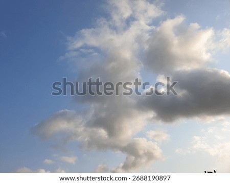A wispy cloud formation against a bright blue sky with soft sunlight illuminating the edges of the clouds and creating a sense of depth and texture in the atmosphere