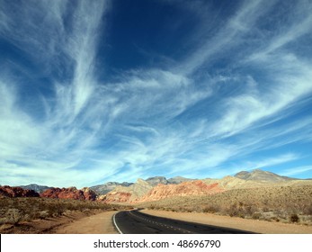 Wispy Clouds Over Red Rocks And Highway In The Vast Deserts Of Nevada, USA.