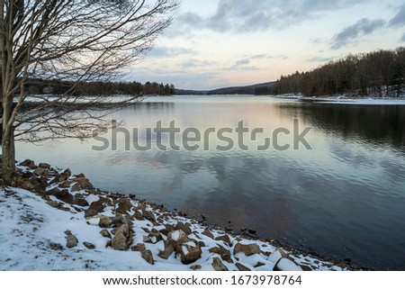 Wispy clouds are reflected in the mirror-like surface of a partially frozen lake in western Maryland.