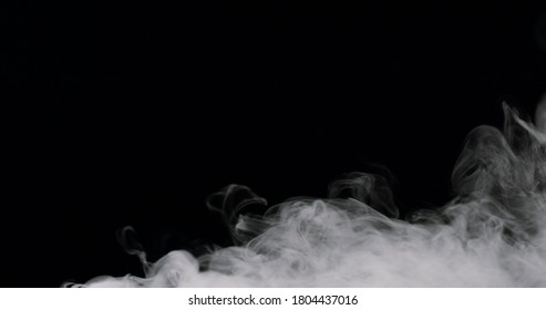 wispy smoke rolling along the bottom of the frame, against a black background.