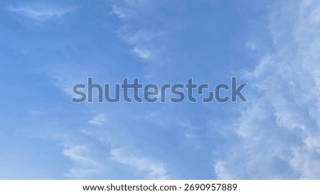 Wispy white clouds drift across a clear blue sky, creating a ser