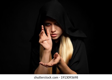 Witch in black mantle on dark background. Scary fantasy character