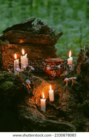 witch cauldron with amulet and burning candles in forest, abstract natural background. occult esoteric magic ritual, witchcraft, wicca. spiritual practice. fairytale, mystery atmosphere