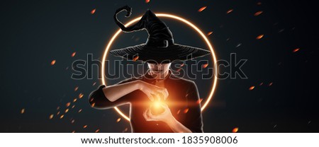 A witch in a hat conjures on a dark background. Halloween concept, magic, website header, copy space